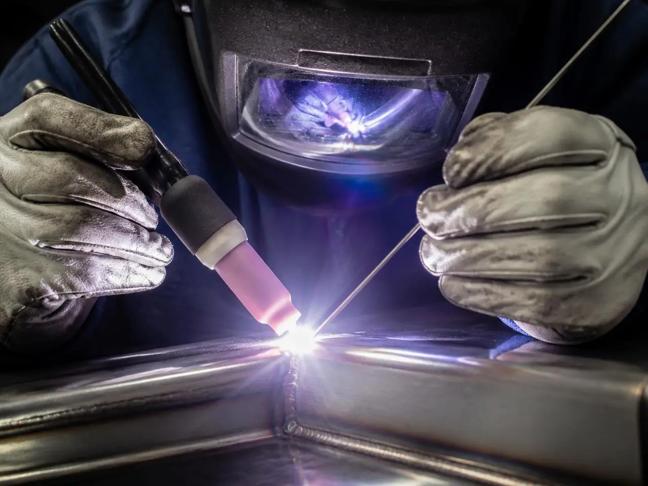 Welder TIG welding a stainless steel joint with a bright arc
